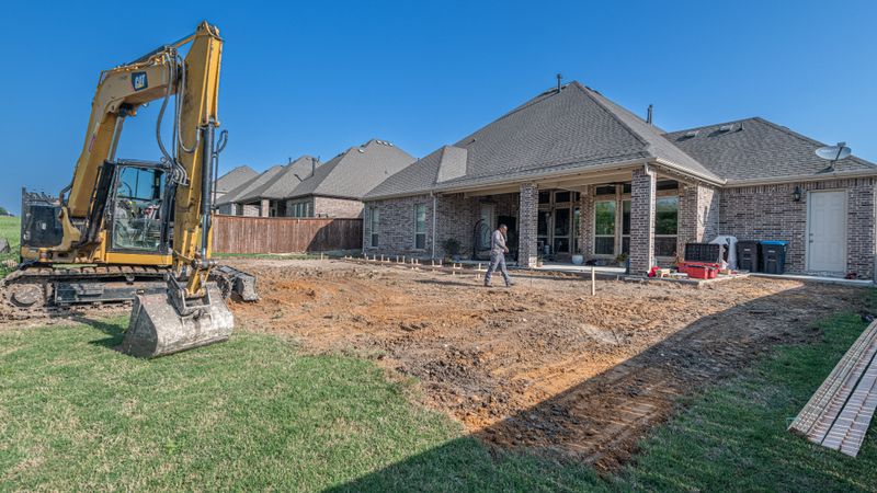 Chantier de piscine enterrée : fouille ouverte et pelle mécanique au bord du terrassement