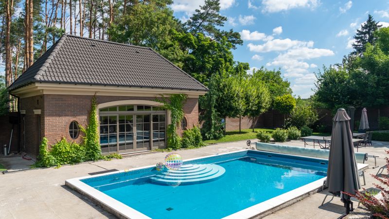 Ligne d'eau d'une piscine privée rectangulaire, margelles claires au premier plan