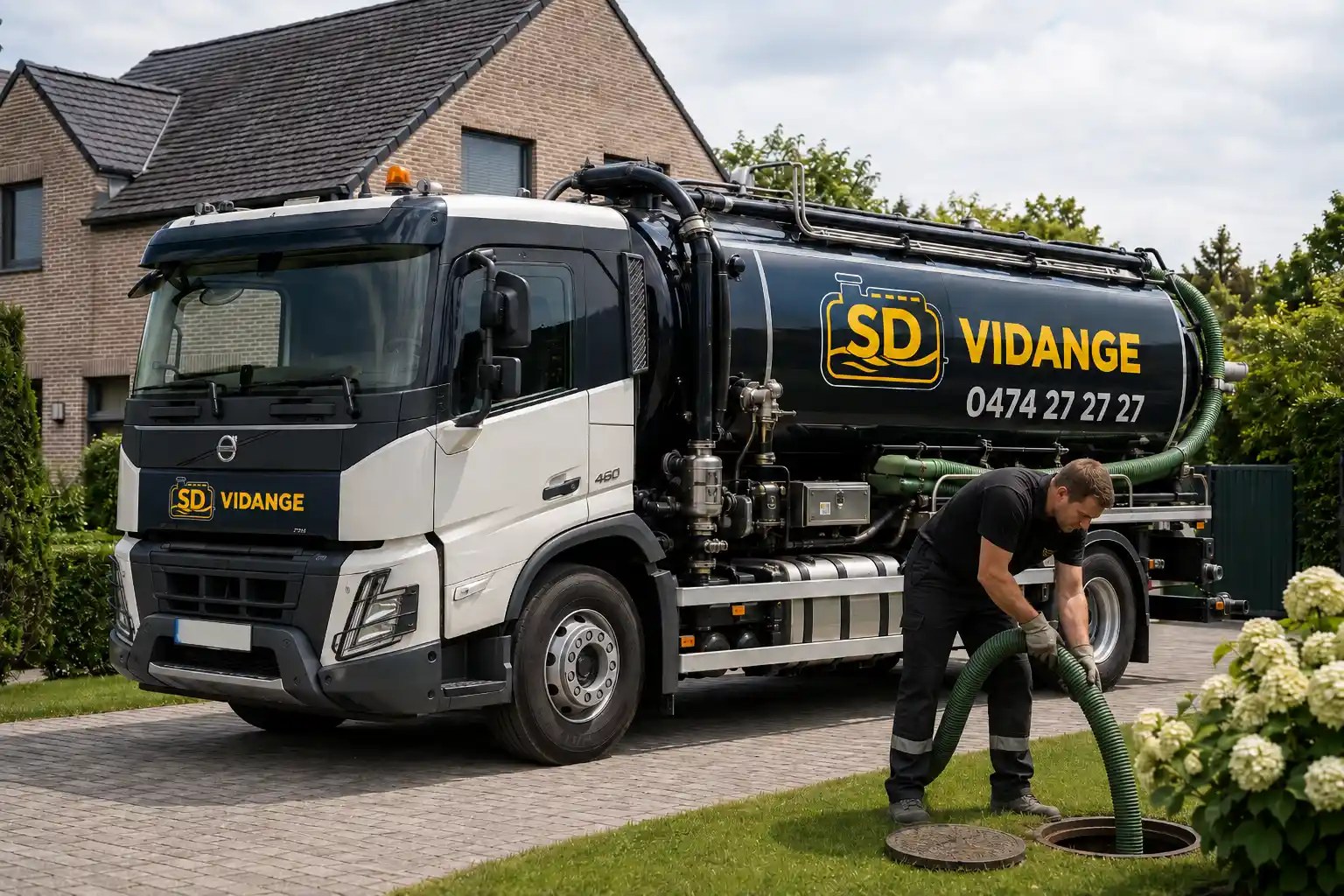 Technicien SD Vidange manipule un tuyau d'aspiration vert devant le camion-citerne dans une allée